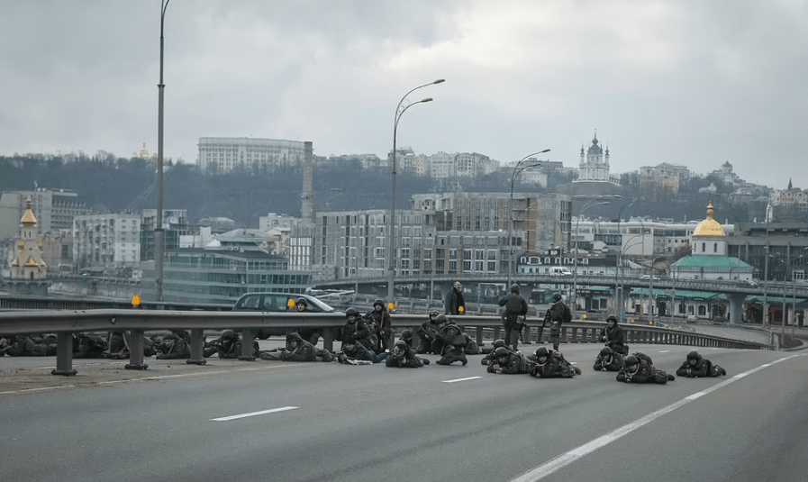 Ukrainian soldiers are seen forming up across a Kyiv highway as they prepare to defend the city against Russian attackers, with gunshots and explosions reported in the capital's central business district.