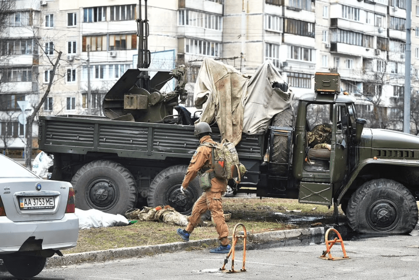A Ukrainian military medic approaches the remains of Russian servicemen dressed in Ukrainian army uniforms lying near and inside a truck following a skirmish in Kyiv, Ukraine.